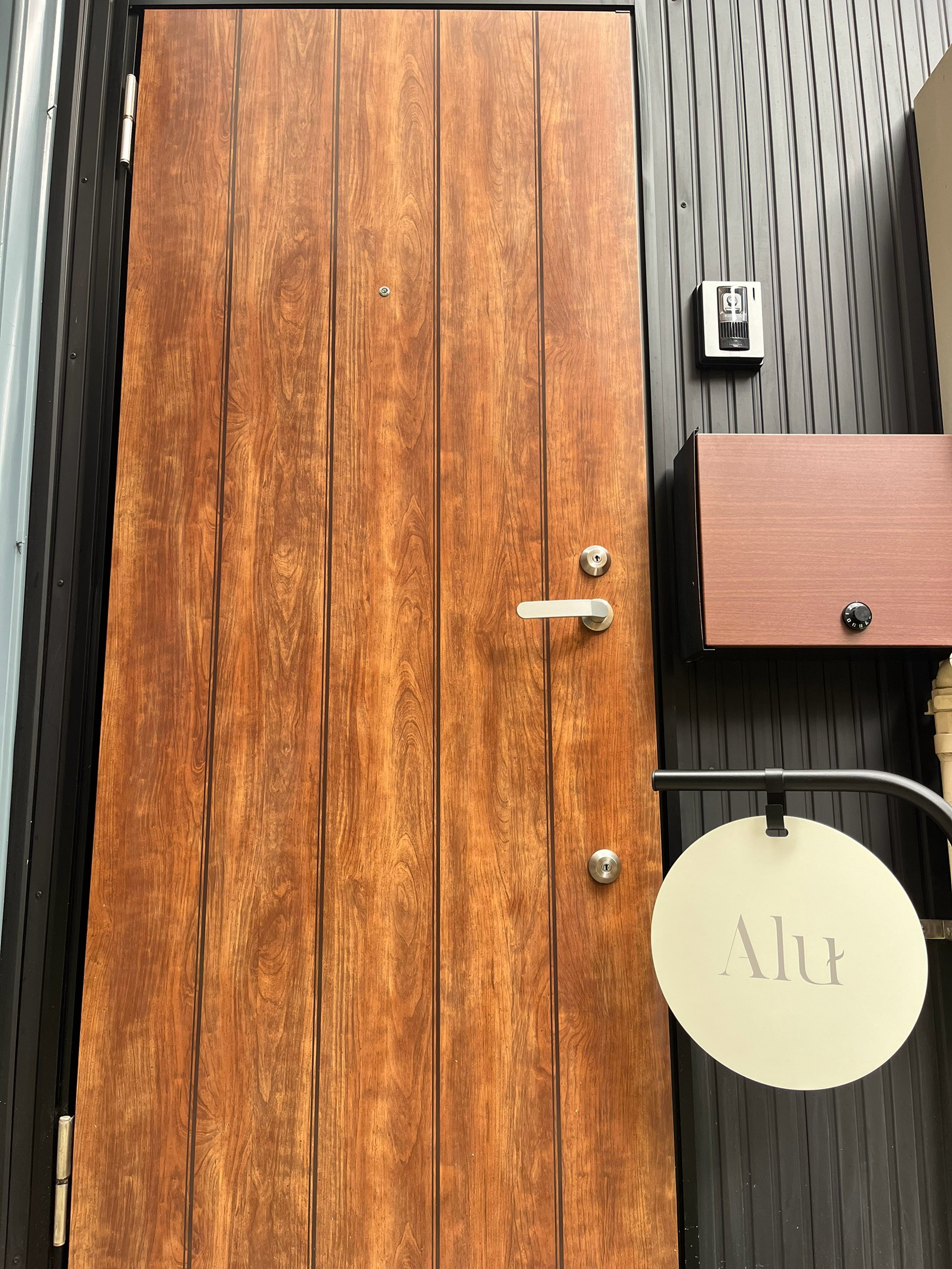 Aluの入口。木の扉と円形の看板